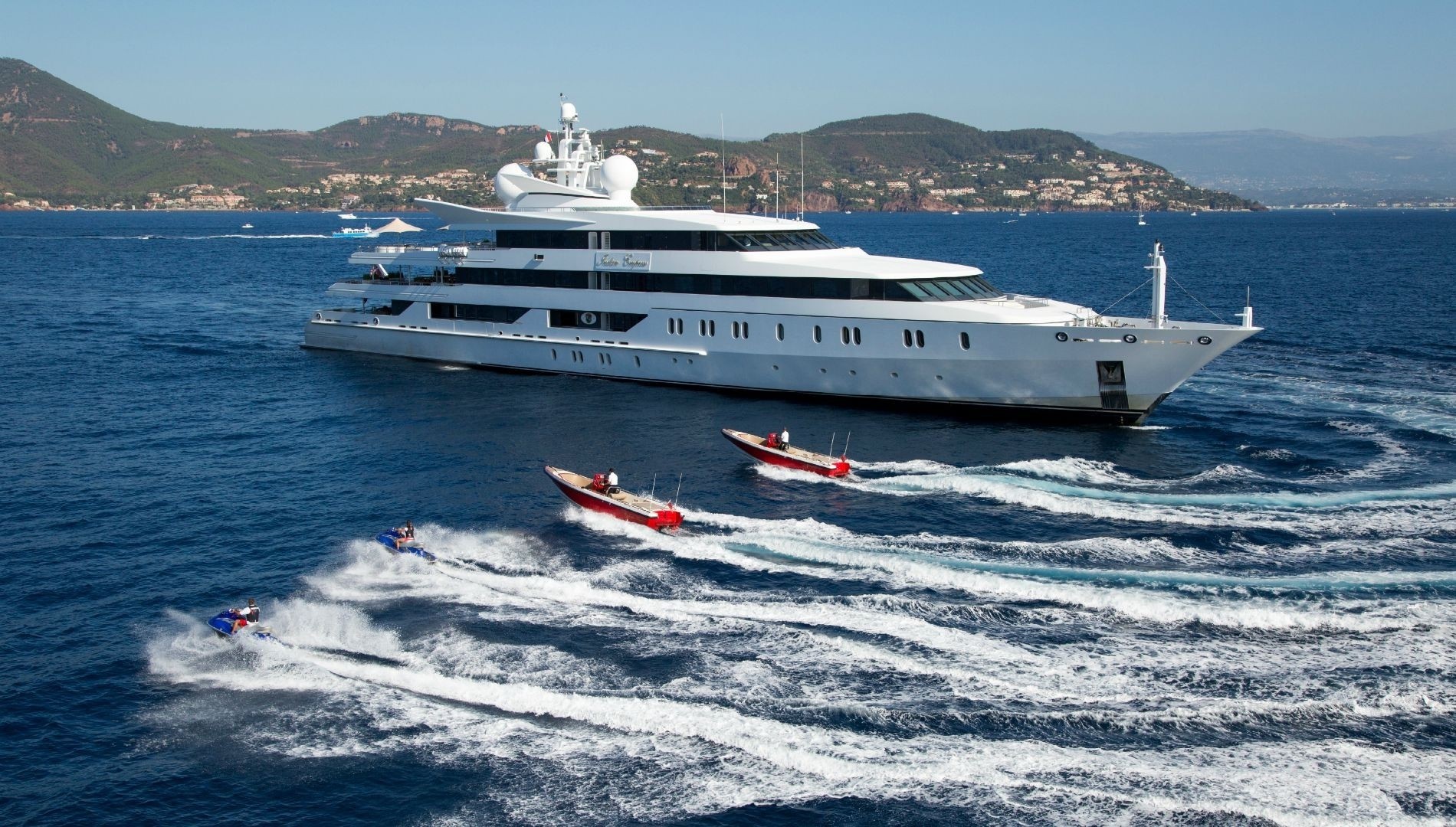 superyacht at anchor with tenders running