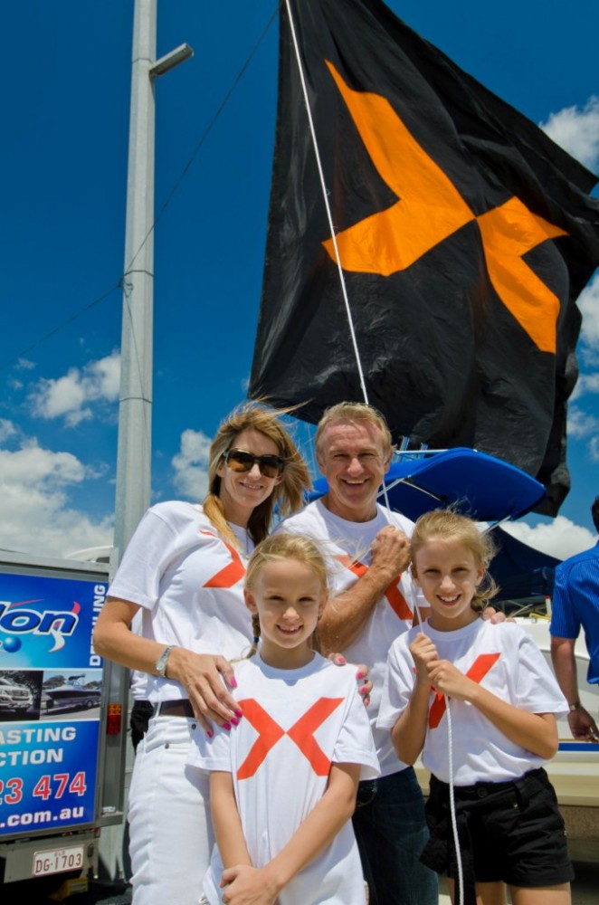 Russell Ingall and family hoist the giant X flag to mark the opening of the Gold Coast Marine Expo