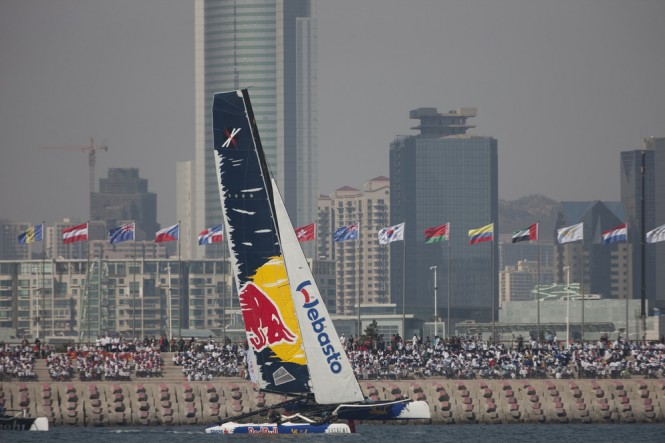 Red Bull Sailing Team flying a hull in front of spectators lining the breakwater in Fushan Bay, Qingdao