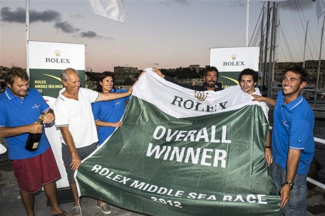 Crew of Hi Fidelity yacht display the flag awarded to the overall winner of the 2012 Rolex Middle Sea Race - Photo by Rolex Kurt Arrigo