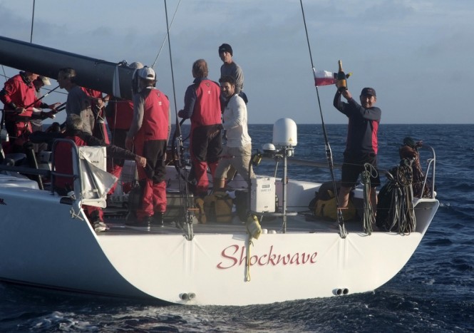 Owner of Shockwave Yacht, George Sakellaris, waving a victory bottle of champagne - Photo by Barry Pickthall